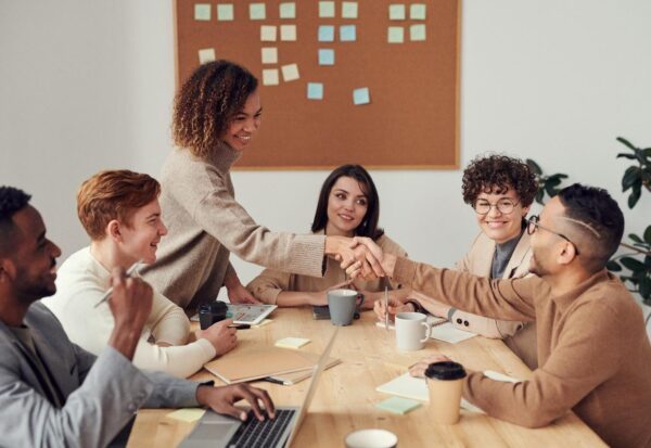 Two team members shaking hands at a meeting after resolving their differences