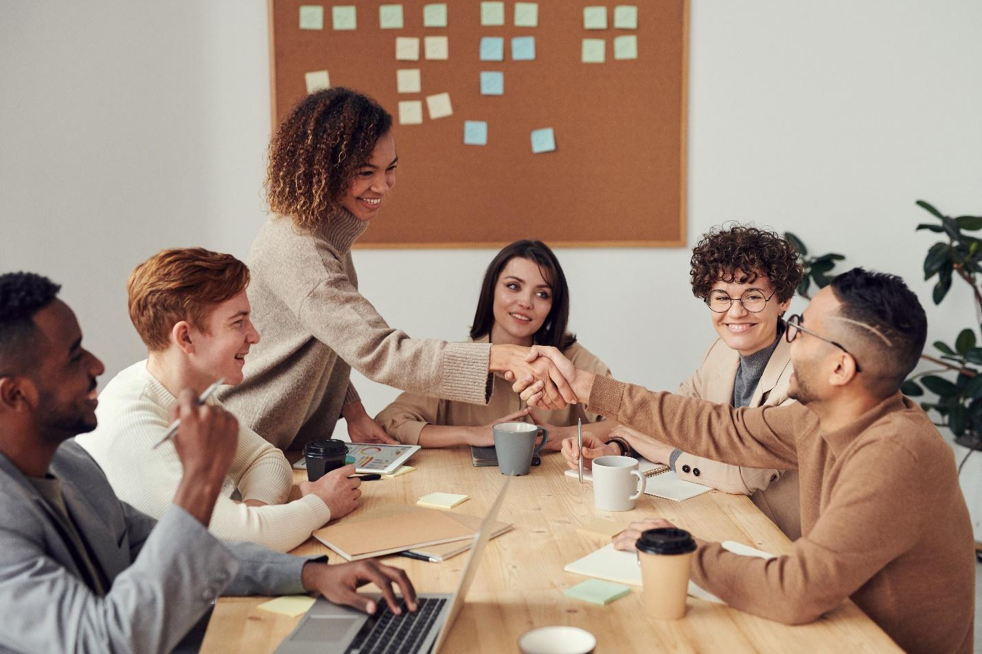 Two team members shaking hands at a meeting after resolving their differences